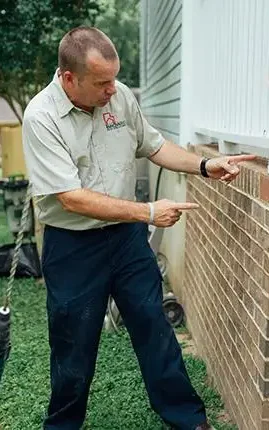 Two Innovative Pest Solutions technicians inspecting the side of a home.