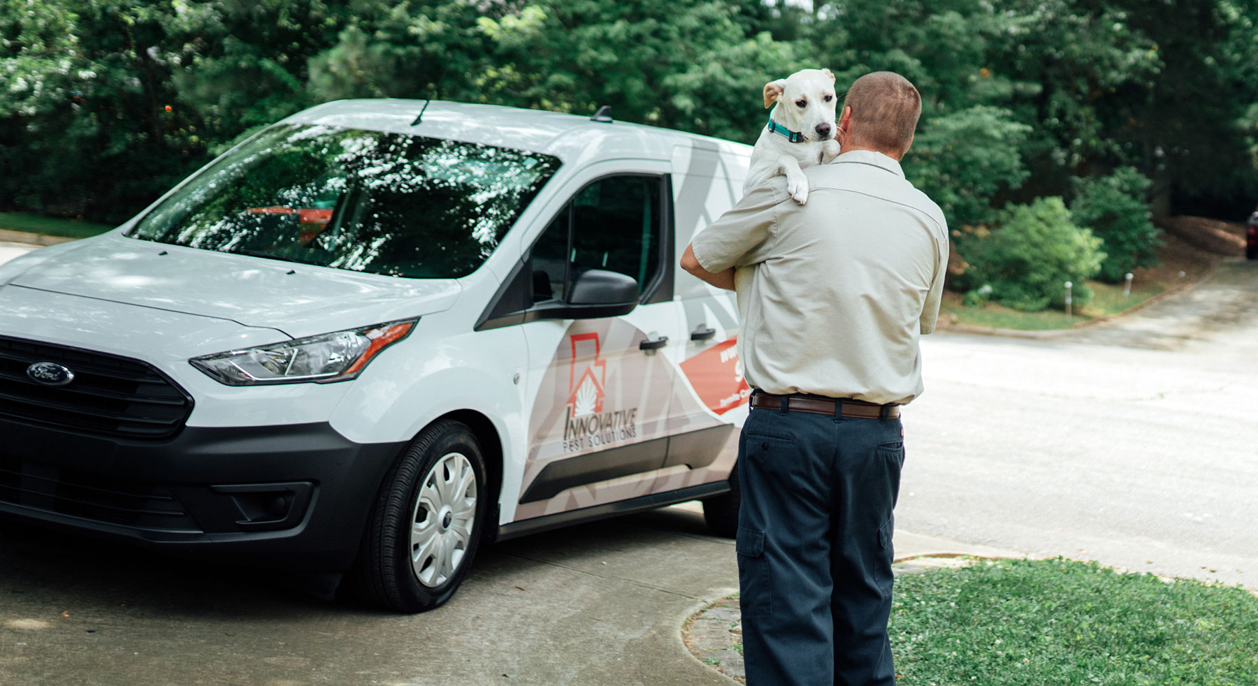 Innovative Pest Solution technician holding a white dog in front of a white van