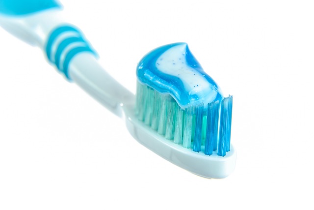 blue and white toothpaste on a white, blue, and green toothbrush