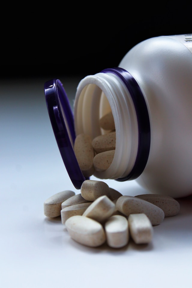 Antihistamine pills spilling out of a white bottle, one of the ways how to treat mosquito bites on dogs