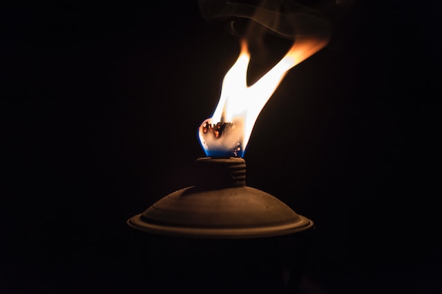 A burning lantern or candle, one of the most popular mosquito-repellent lights, with a bight red flame against black background.