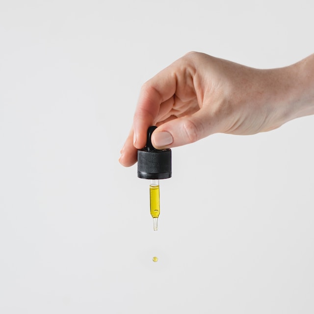 Person holding a dropper containing peppermint oil for roaches