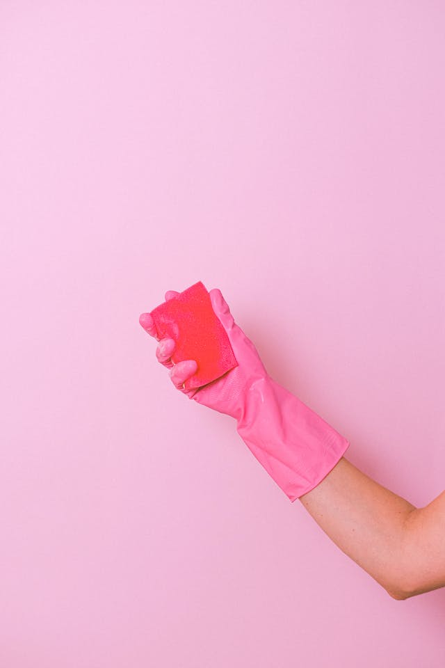 A person wearing pink gloves holding a sponge