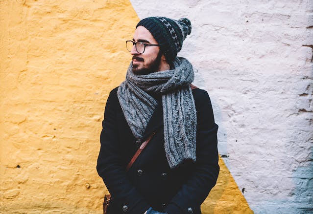 Man in front of a yellow and white wall wearing cold weather clothing