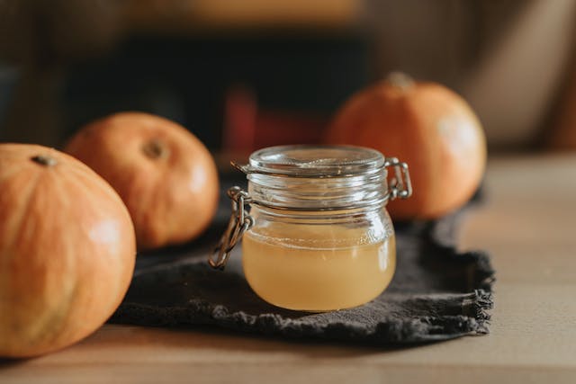 Jar of apple cider vinegar alongside old apples